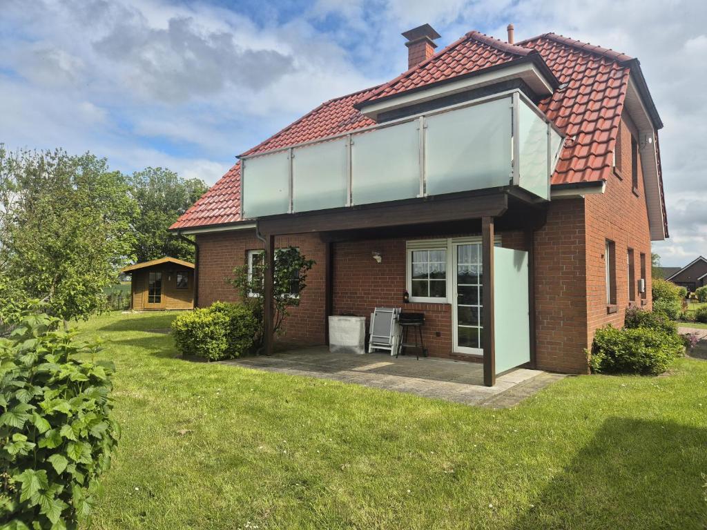 a house with a red roof and a lawn at Feldblick in Krummhörn