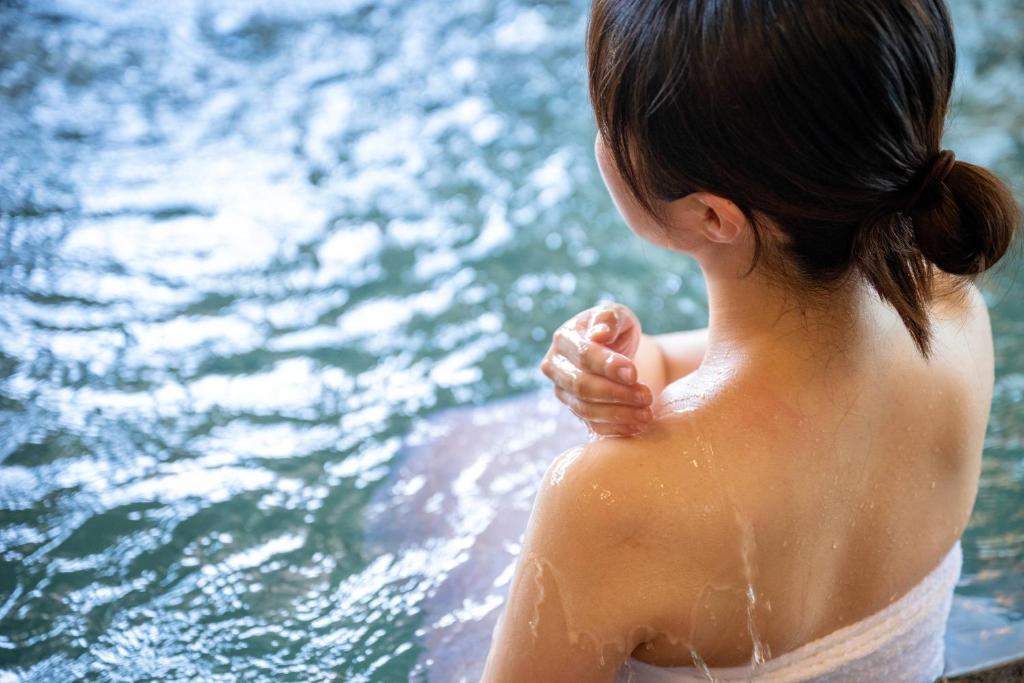 a woman standing in front of a body of water at 六日町温泉 龍氣 in Minami Uonuma