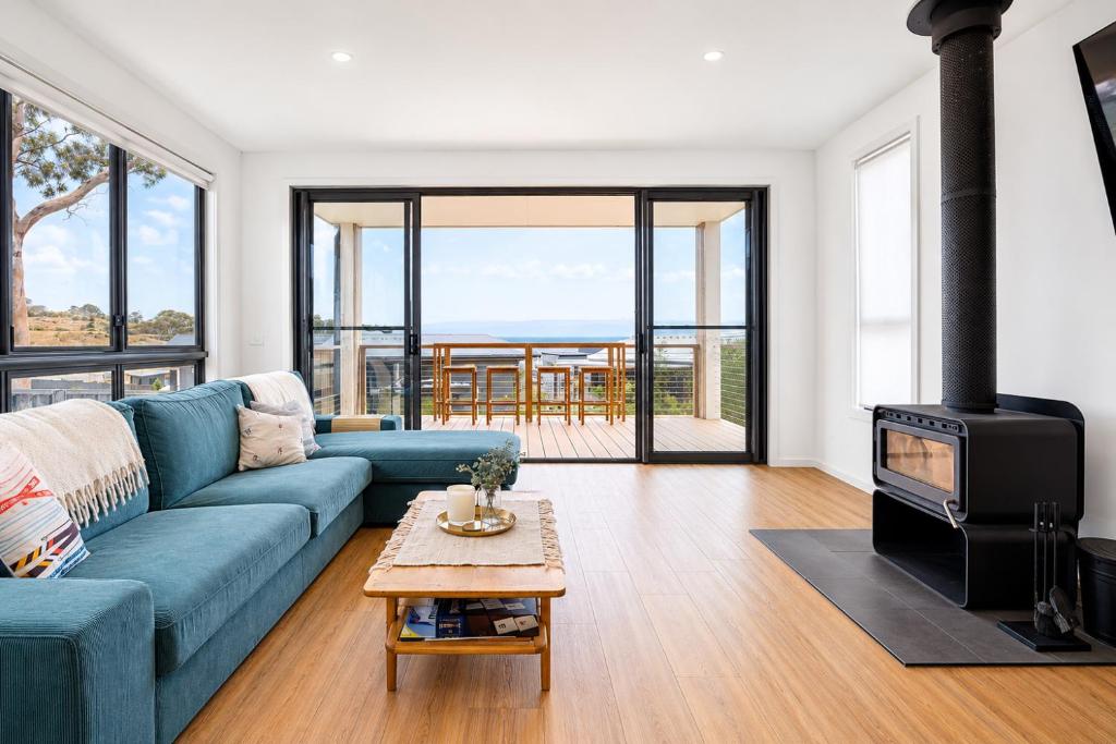 a living room with a blue couch and a fireplace at Snowy Lake Haven in Jindabyne