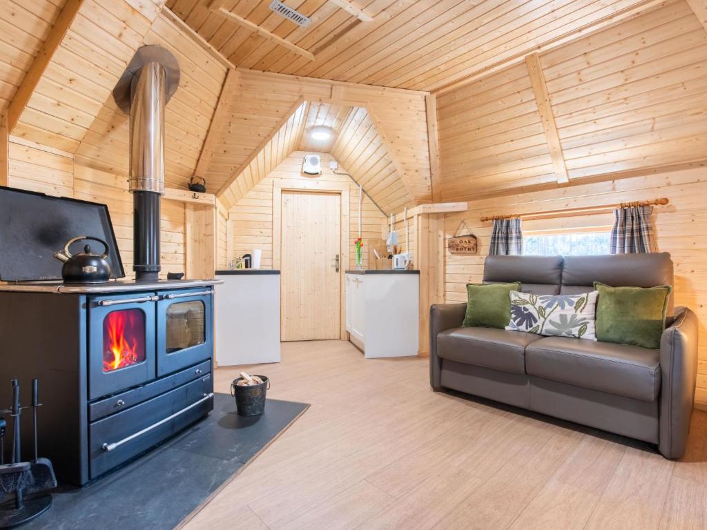 a living room with a couch and a stove at Chalet Oak Bothy by Interhome in Coldstone