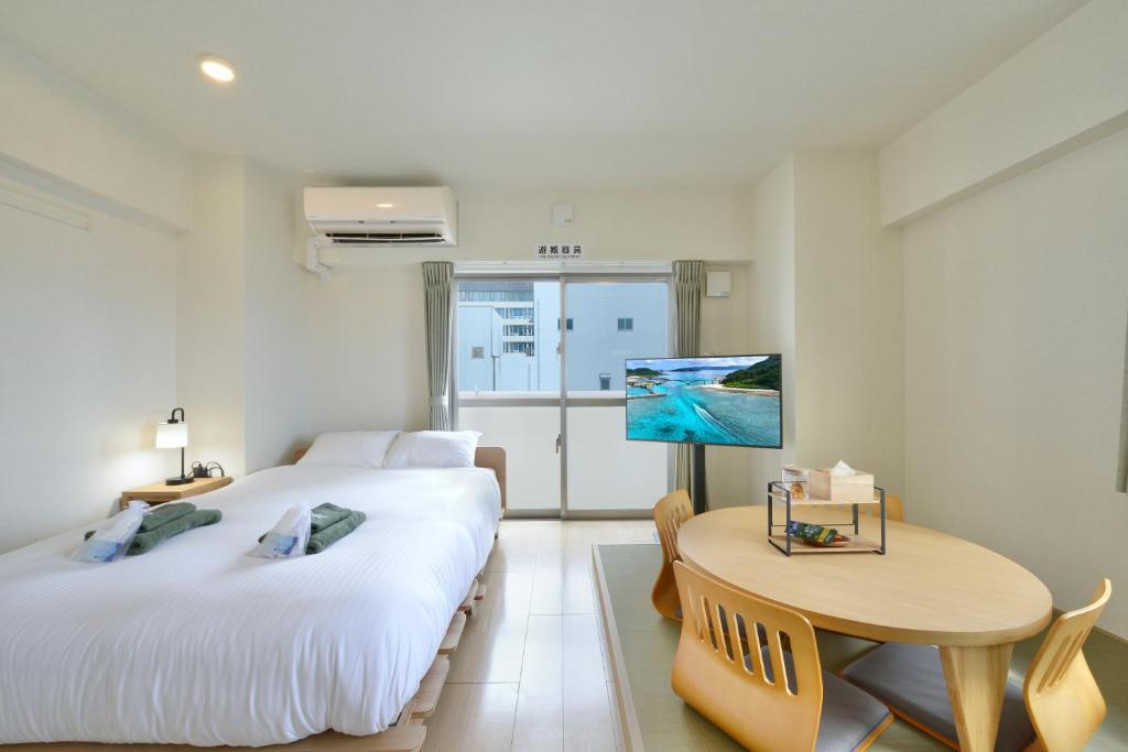 a hotel room with two beds and a table and a desk at Hotel HIRAKU RYUKYU -STYLE- in Naha