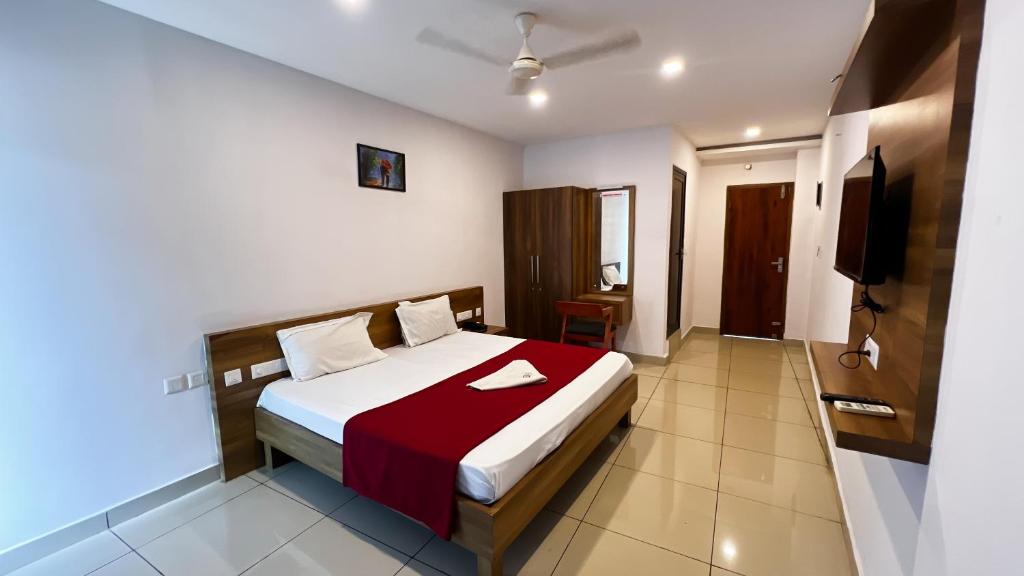 a hotel room with a bed with a red blanket at Peacock residency in Edavanna