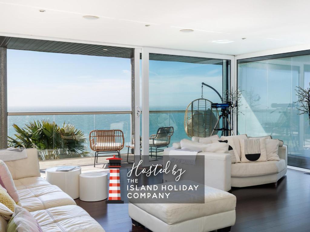 a living room with white furniture and large windows at Kittiwake - Ventnor Bay with Hot Tub in Ventnor