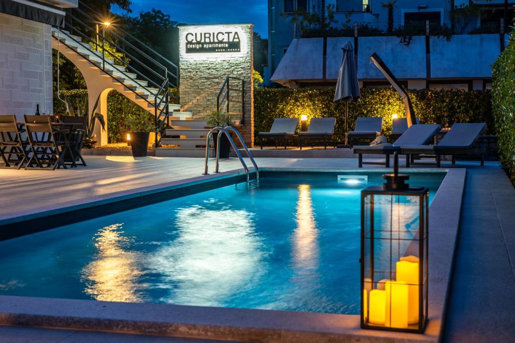 a swimming pool at night with a light in the middle at CURICTA Design Apartments in Krk