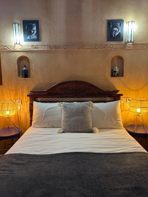 a bedroom with a large bed with two lamps at Berber Nomad Kasbah in Nkob