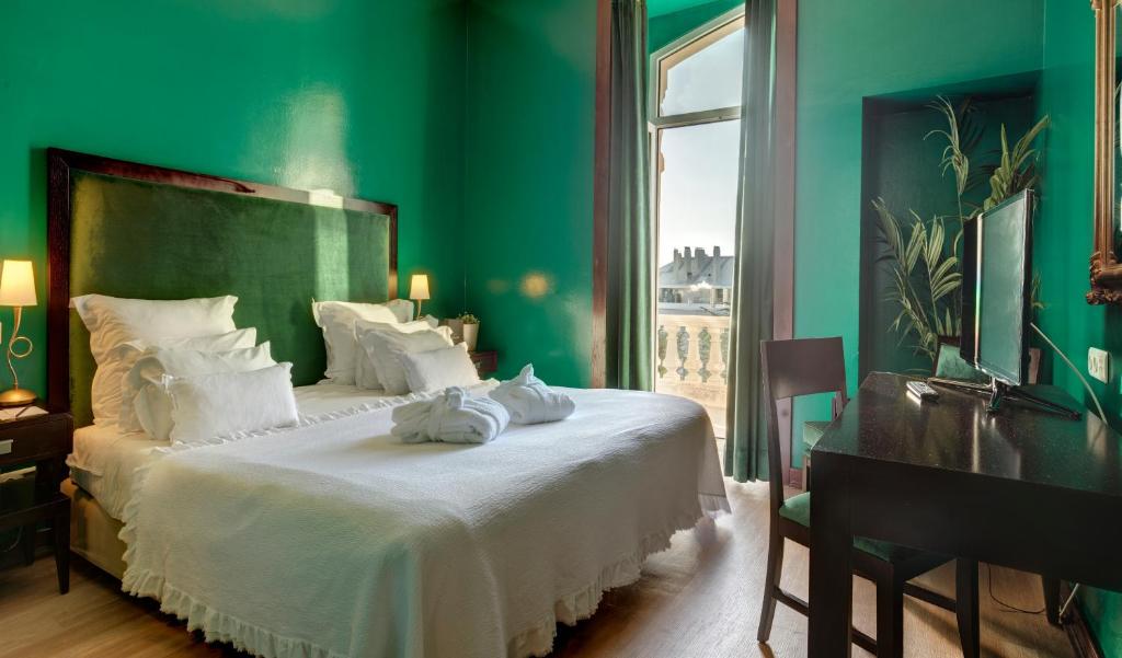 a green bedroom with a large bed with white pillows at Hotel Inglaterra - Charme & Boutique in Estoril