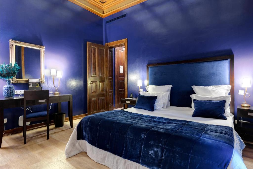 a blue bedroom with a large bed and a desk at Hotel Inglaterra - Charme & Boutique in Estoril