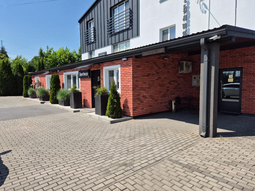 a brick building with potted plants in front of it at Willa "Aparthause" E-Apartamenty in Mielec