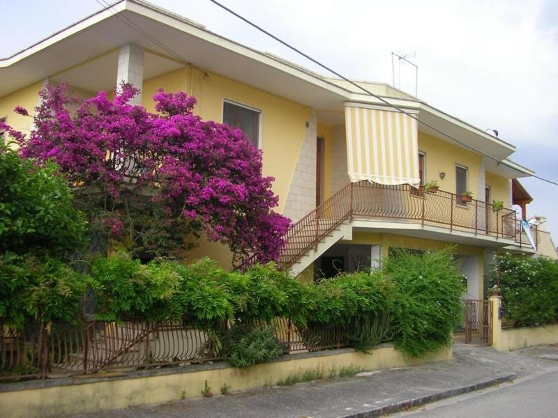 a building with purple flowers on the side of it at Orsa Maggiore apartment with private courtyard in Uggiano la Chiesa