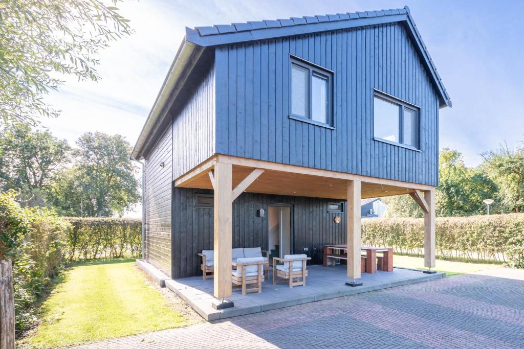 a house with a blue roof and a patio at De Goudbalpeer - Ruim en luxe vakantiehuis voor 6 personen met uitzicht op wijngaard in Ruinerwold