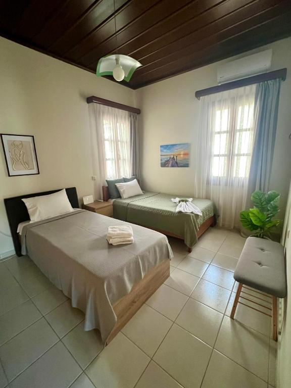 a bedroom with two beds and a chair and windows at Lagom House in Panagia