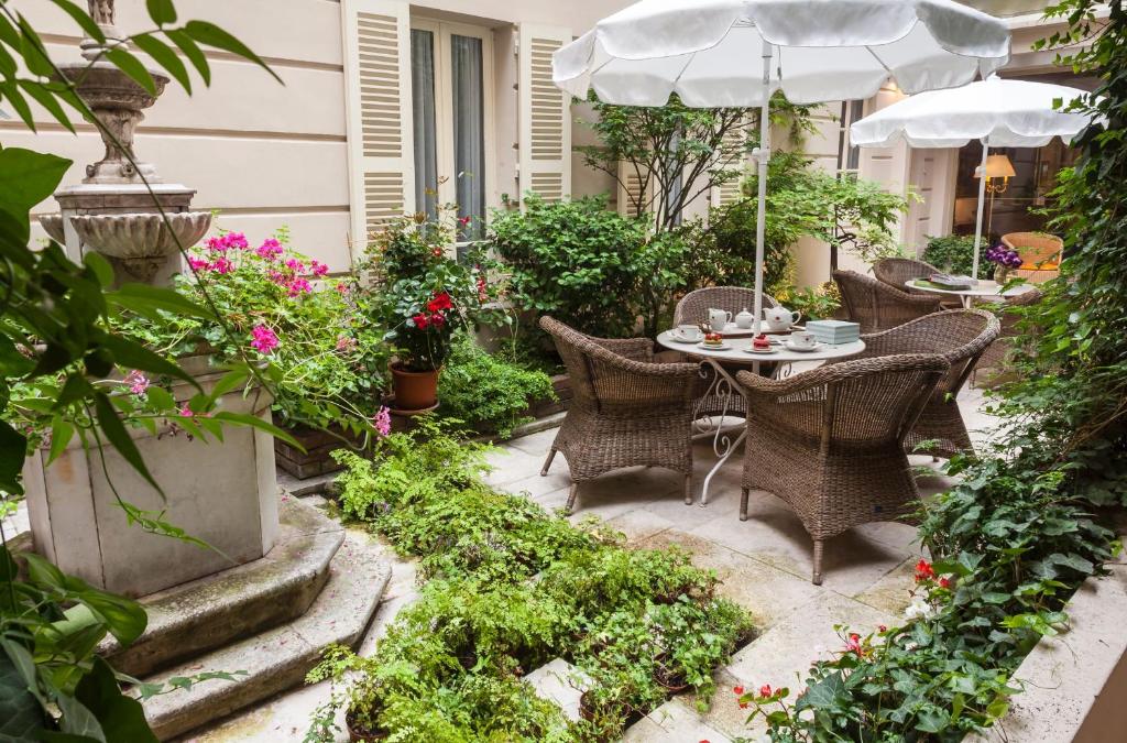 
a garden area with tables, chairs, and umbrellas at Hotel d'Angleterre in Paris
