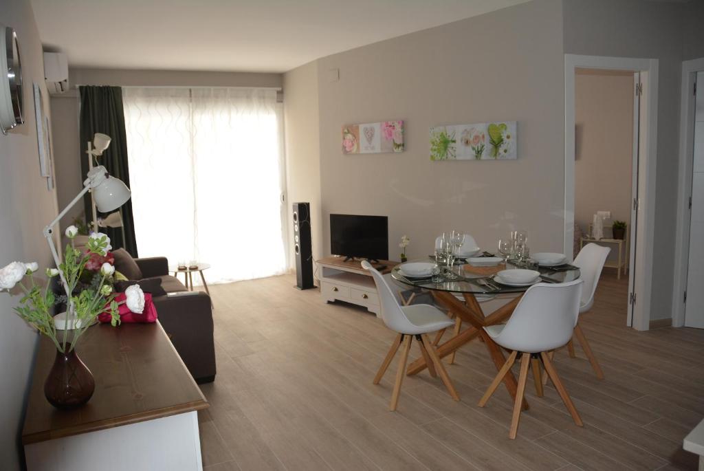 sala de estar con mesa de comedor y sillas blancas en Apartamento Flavia II Sant Damià, en Sitges