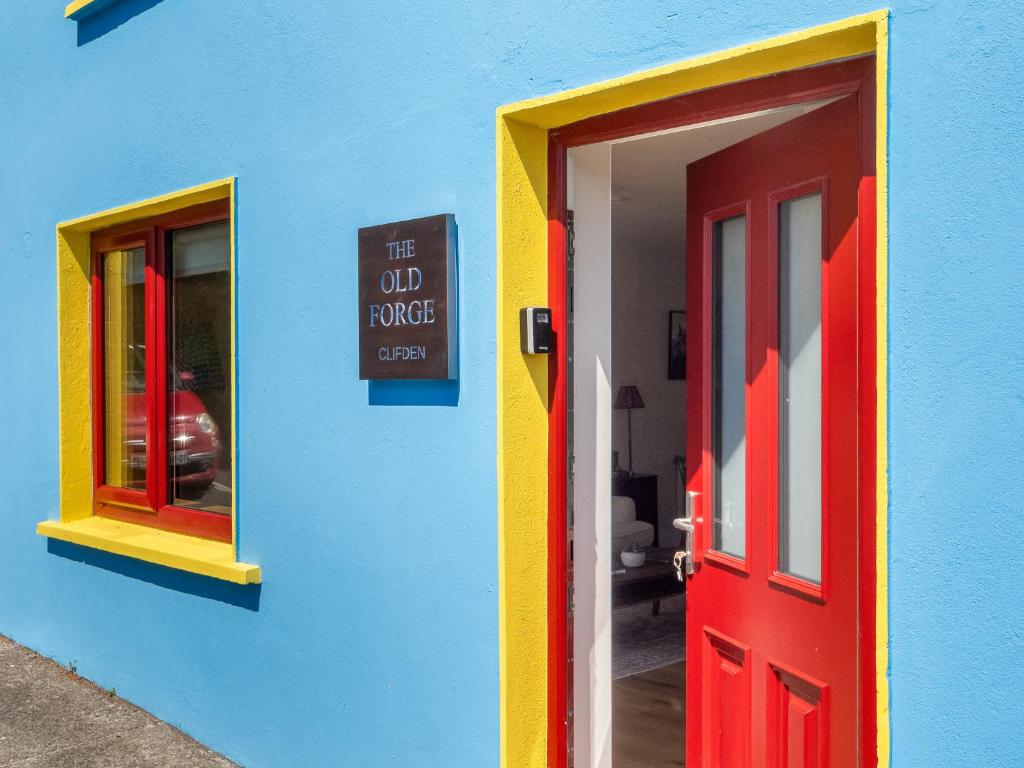 a colorful building with a red door and a sign at The Old Forge Clifden in Clifden