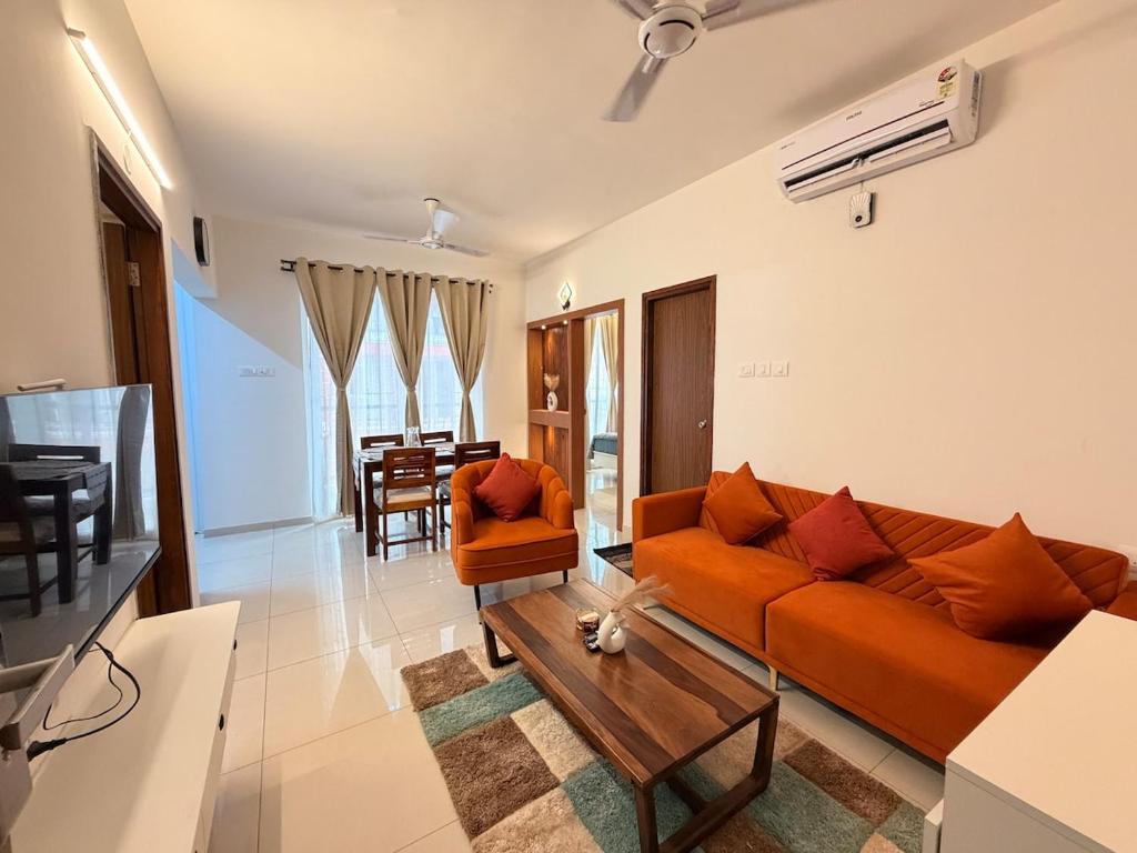 a living room with an orange couch and a table at Casa sol Goa 2BR Apt By Amoret Homes in Chicalim