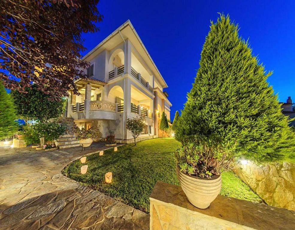 a large house with two potted trees in a yard at Golden Coast Boutique - Luxury Living in Kypseli