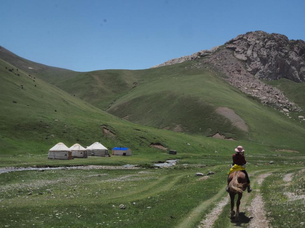 a person riding a horse down a dirt road at Mamyr Guest House in Sary-Mogul