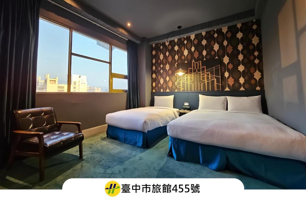 a bedroom with two beds and a chair and a window at Modern Inn in Taichung