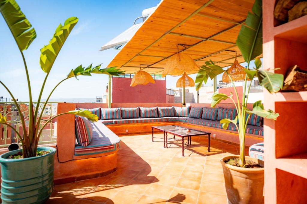 a patio with a couch and a table and plants at Wave chaser surfhouse morocco in Agadir