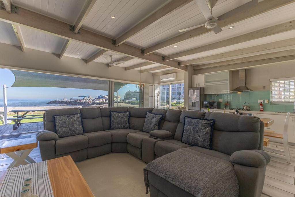 a living room with a large couch and a kitchen at 8 On Fleur Park Beach in Gordonʼs Bay