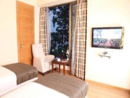 a bedroom with a bed and a window with a chair at Middleton Inn in Kolkata