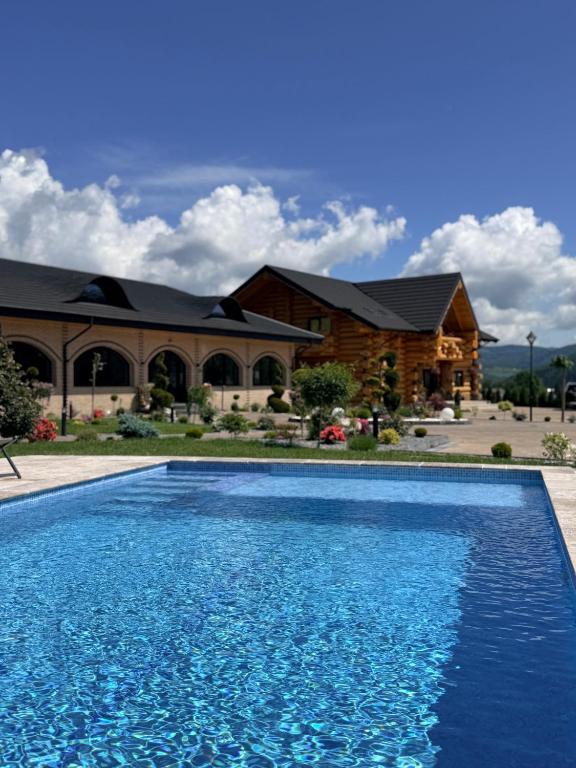 a blue swimming pool in front of a house at Bucovina Exclusiv in Vama