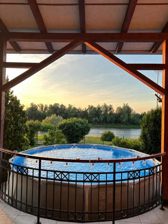 a hot tub on a balcony with a view of a river at Vikendica Dva labuda in Banoštor