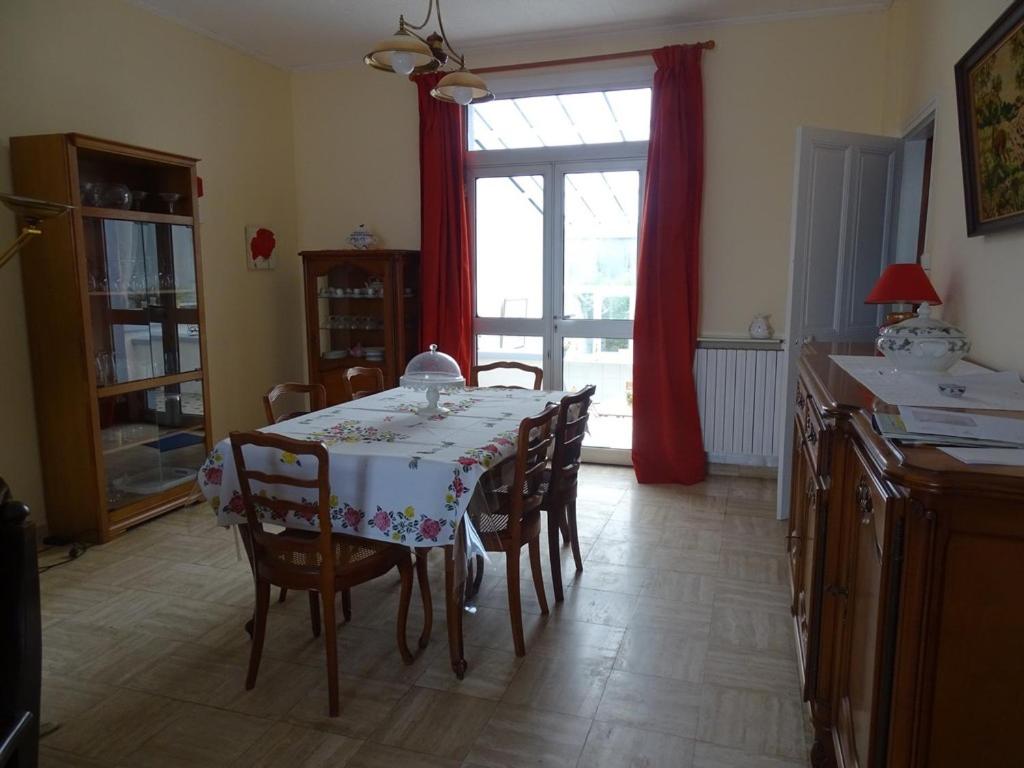a dining room with a table and chairs and a window at Roses de Picardie in Chauny