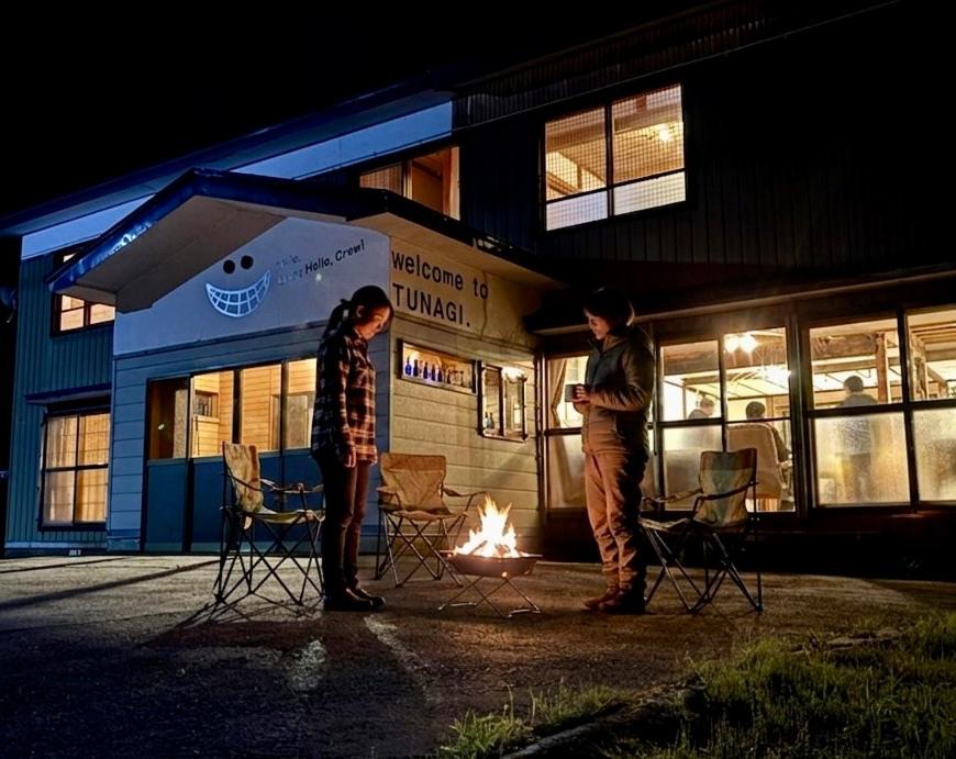 two people standing next to a fire in front of a bus at 静かな森の古民家ステイ Tunagiつなぎ in Nishiwaga
