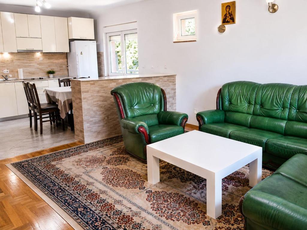 a living room with green leather furniture and a white table at Udoban porodični apartman ViS Raška, 80m2, parking, bašta in Raška