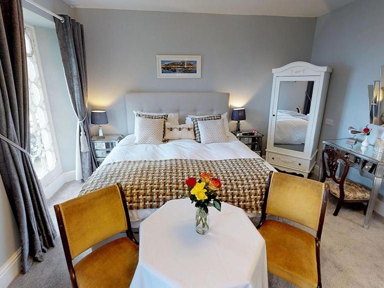 a bedroom with a bed and a table with flowers on it at Ranscombe House in Brixham