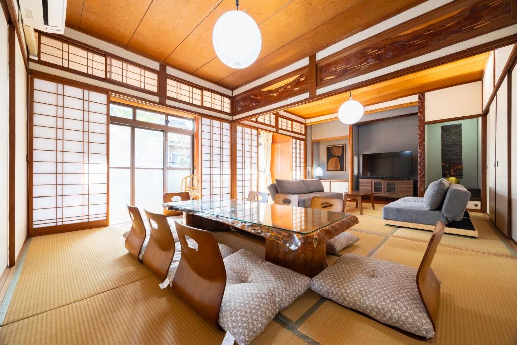 a living room with a glass table and chairs at 湯のん - Yunon - 温泉付き一棟貸し古民家 指宿名物 砂むし温泉徒歩2分 最大11名 in Ibusuki
