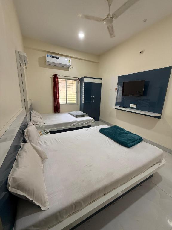 two beds in a room with a tv on the wall at Shada Shiv Heritage, Omkareshwar in Godarpura