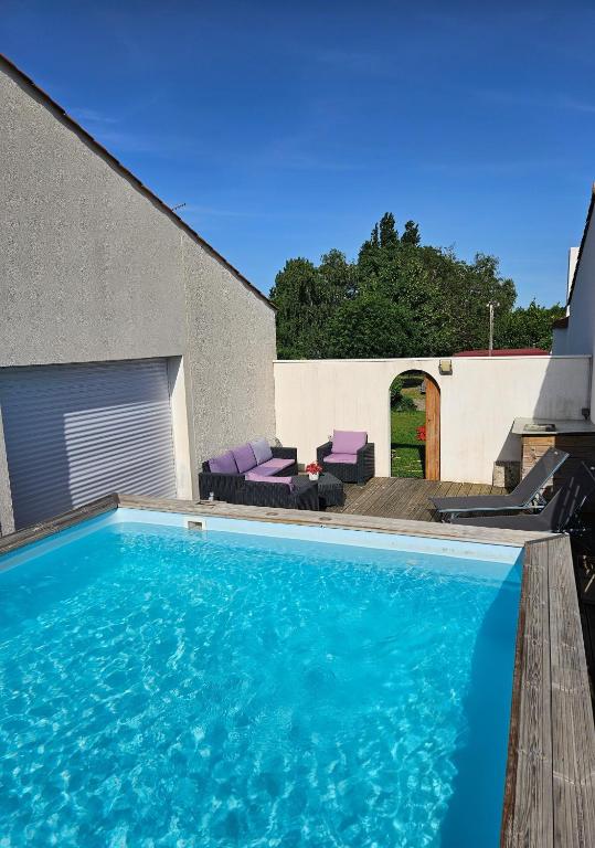 a swimming pool with purple chairs and a house at Les Renaudelles in Angles