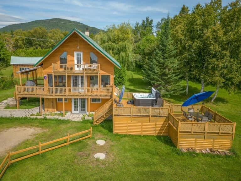 a large home with a large deck and a house at Spa Pool table Mountain view - Martine-54 in Petite-Rivière-Saint-François