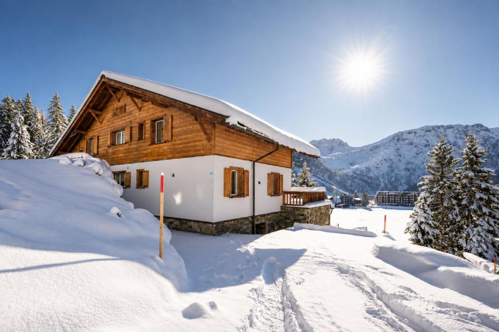 a log cabin in the snow with the sun behind it at Sans Souci EG - Alpenblick & Obersee Panorama - by Arosa Stay in Arosa