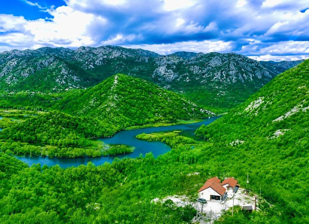 a mountain valley with a river and a house at S&M Apartments in Rijeka Crnojevića
