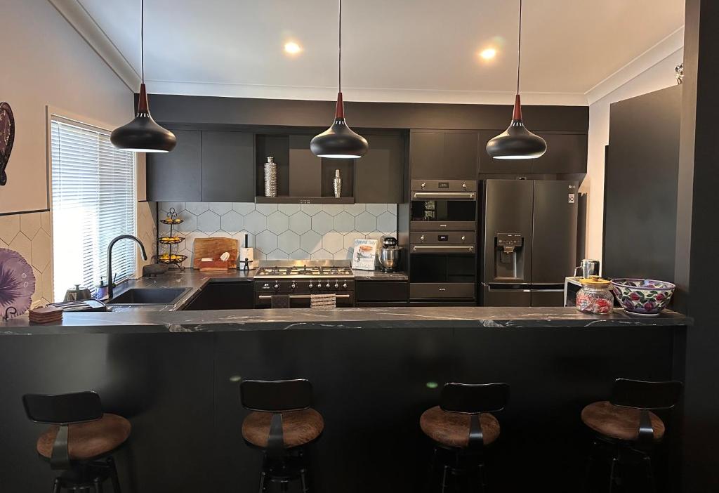 a kitchen with a sink and a counter with bar stools at Among The Trees Guest Suite in Kooralbyn