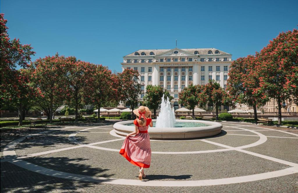 a woman in a dress standing in front of a fountain at Esplanade Zagreb Hotel in Zagreb
