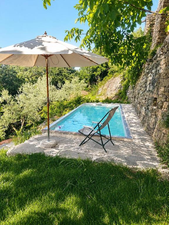 an umbrella and a chair next to a swimming pool at Ca Rivetta in Pezzolo Valle Uzzone