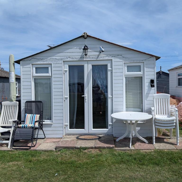 a small white shed with a table and chairs at The Lighthouse Chalet in Leysdown-on-Sea
