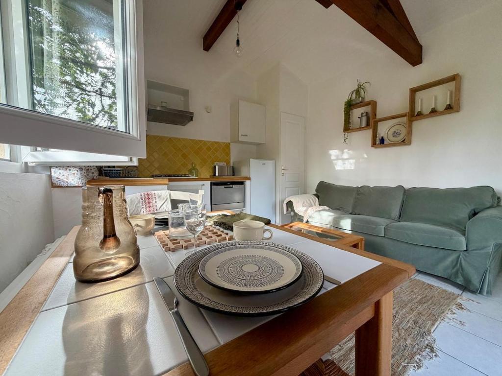 a kitchen and living room with a table and a couch at Maisonnette près du lac in Léon