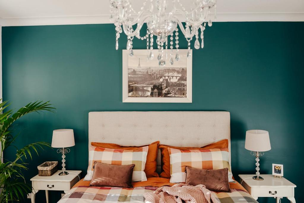 a bedroom with a bed with blue walls and a chandelier at Green Gables Bed and Breakfast in Cygnet