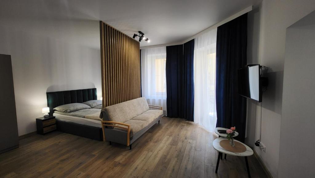 a bedroom with a bed and a couch and a tv at Apartamenty Centrum Plac Wolności ApartHotel wyjątkowy in Kielce
