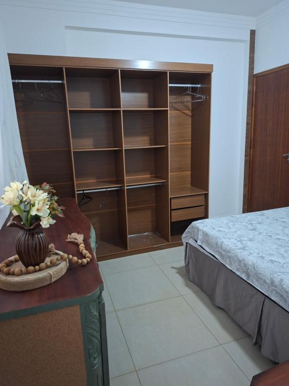 a bedroom with a bed and a table with flowers on it at confortável suite no jardim Botânico in Ribeirão Preto