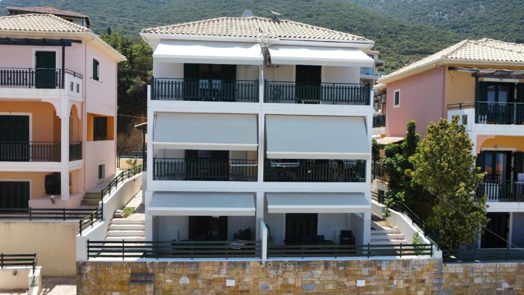 a white apartment building with balconies and trees at Reis Villa in Nikiana