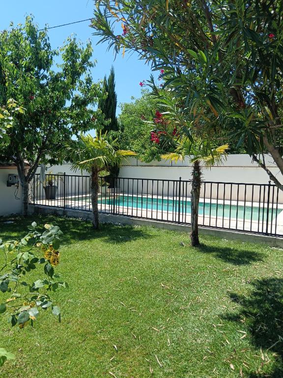 a fence in front of a yard with trees at Charmant cocon tout équipé in Carpentras