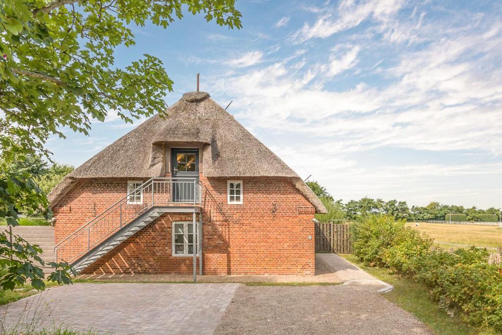 ein altes Backsteingebäude mit einem Strohdach in der Unterkunft Beach-Loft in Wobbenbüll