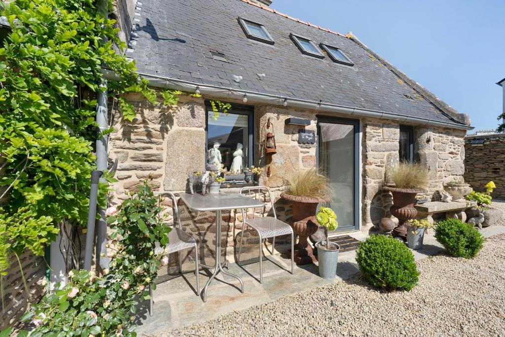 a stone house with a table and chairs in a yard at La maisonette Ti Arzou in Le Conquet