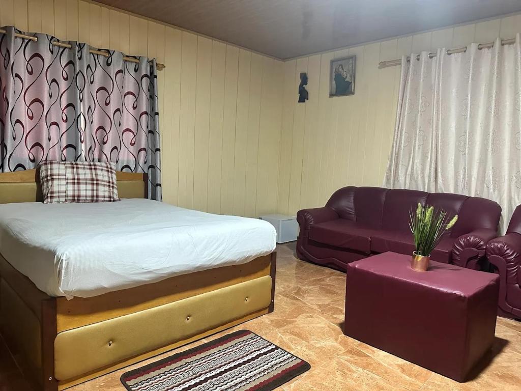 a bedroom with a bed and a couch at Pensão Aragão & Lima in São Tomé